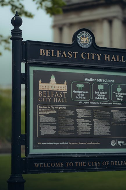 There is no flower arrangement or floral content in the provided image of a Belfast City Hall sign with information about visitor attractions, tours, and regulations. The focus is on a dark blue sign 